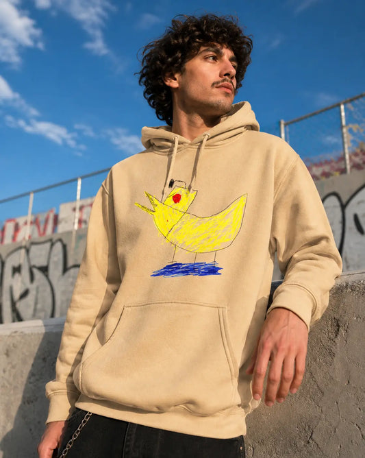 Person wearing a beige hoodie with a colorful duck design outdoors against a blue sky.