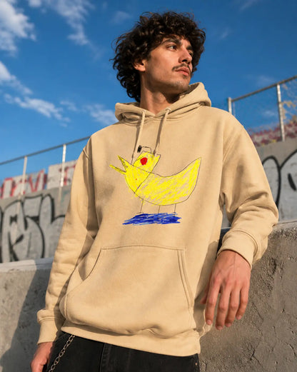 Person wearing a beige hoodie with a colorful duck design outdoors against a blue sky.