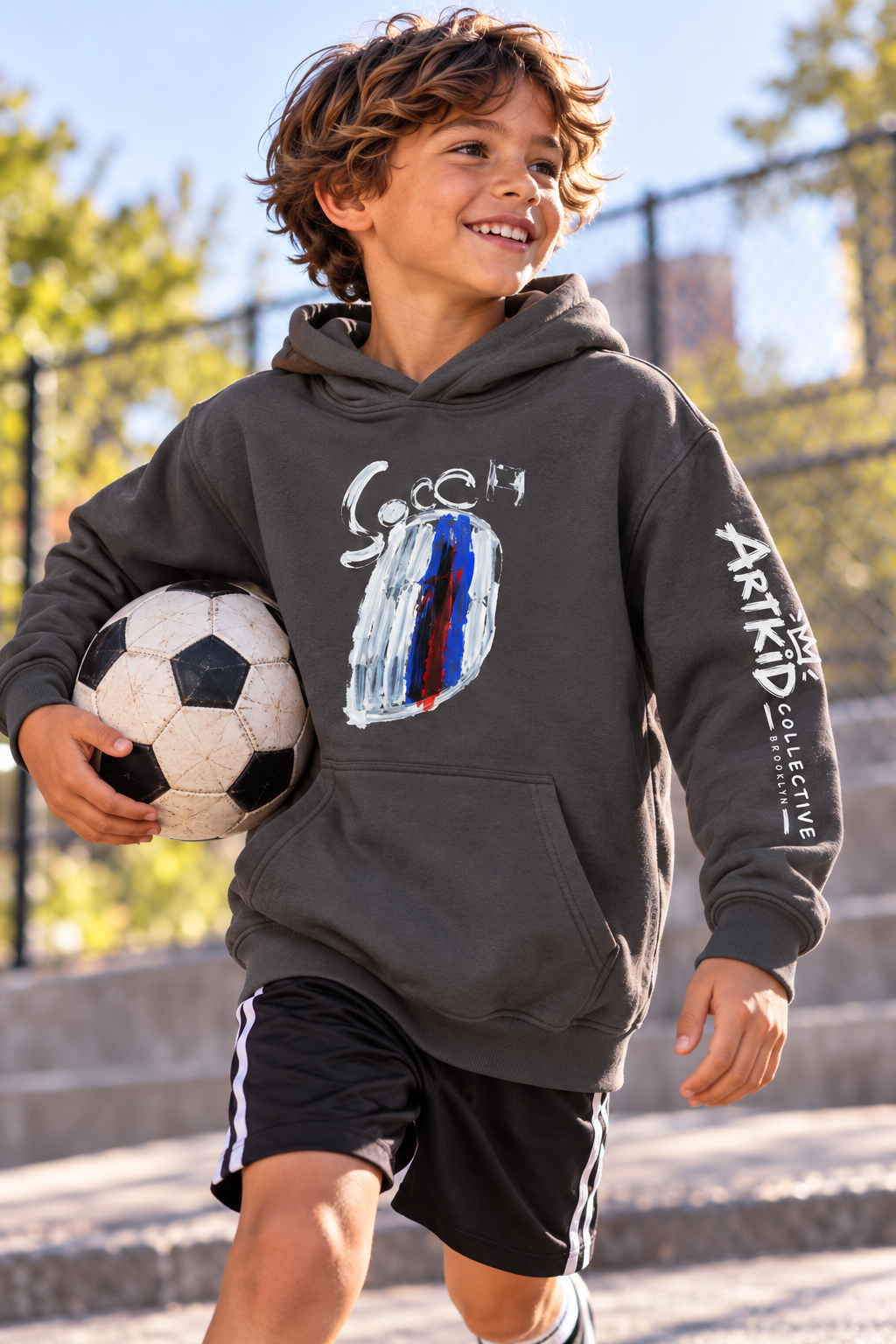 Kid wearing the Goal soccer graphic hoodie with original child-drawn artwork outdoors